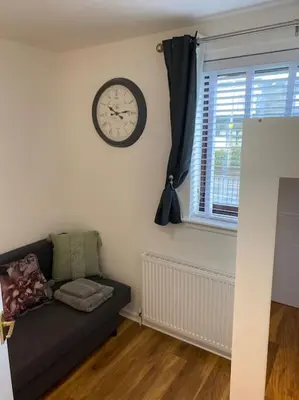 a living room with a couch and a clock on the wall at Perfectly situated luxury 2 bedroom apartment in Glasgow