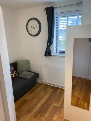a living room with a couch and a clock on the wall at Perfectly situated luxury 2 bedroom apartment in Glasgow