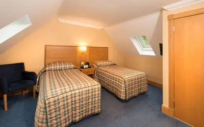 a hotel room with two beds and a chair at Loch Awe Hotel in Dalmally