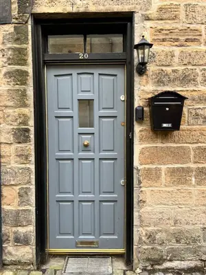 a gray door on a brick building with a window at Very Central, Charlotte Square, near the Castle in Edinburgh