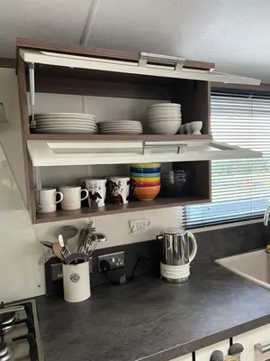 a kitchen counter with plates and cups on shelves at Maneight Luxury Lodge with hot tub in New Cumnock