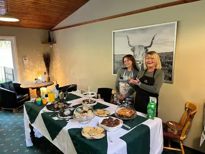 two women standing next to a table with food on it at Cruachan Caravan and Camping Farm in Killin