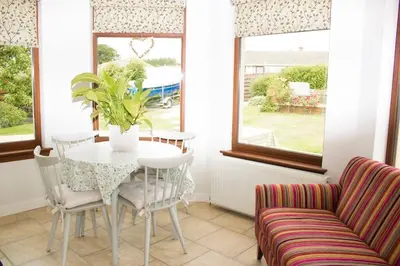 a dining room with a table and chairs and a couch at Pear Tree Cottage in Limekilns