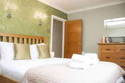 a bedroom with a white bed with towels on it at Pear Tree Cottage in Limekilns