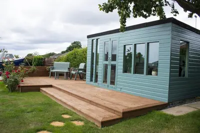 a small blue tiny house with a wooden deck at Pear Tree Cottage in Limekilns
