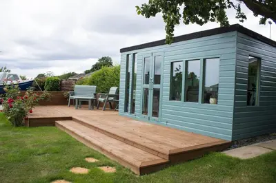 a small blue tiny house with a wooden deck at Pear Tree Cottage in Limekilns