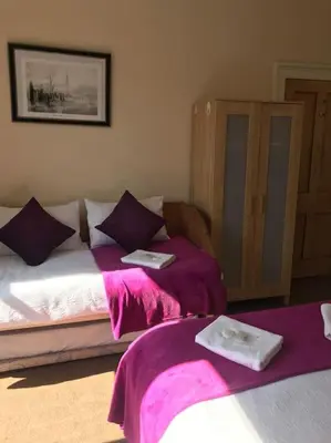 two beds in a room with purple sheets and towels at Central 3 bedrooms apartment for upto 6 in Edinburgh
