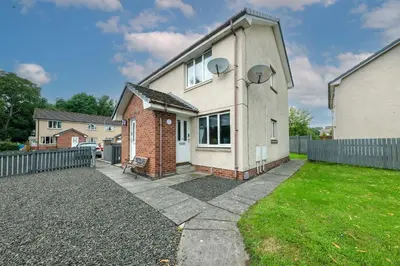 a white house with a fence and a yard at Pure Apartments Commuter- Dunfermline South in Fife