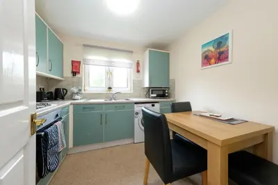 a kitchen with blue cabinets and a wooden table at Pure Apartments Commuter- Dunfermline South in Fife