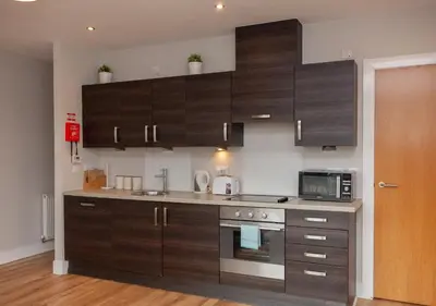 a kitchen with brown cabinets and a microwave at 1 Bedroom Flat in the Heart of Merchant City in Glasgow