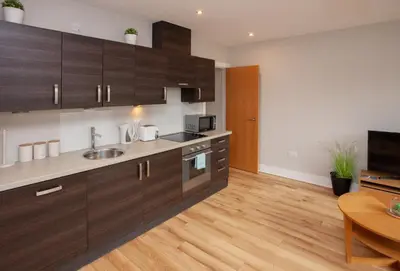 a kitchen with brown cabinets and a wooden floor at 1 Bedroom Flat in the Heart of Merchant City in Glasgow
