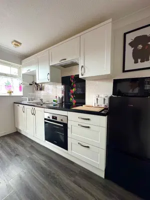 a kitchen with white cabinets and a black refrigerator at FINN VILLAGE 
