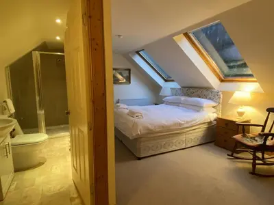 a attic bedroom with a bed and a bathroom at Glen Cottage in Comrie
