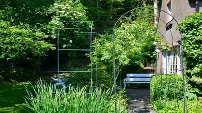 a garden with a bench and a glass trellis at Glen Cottage in Comrie