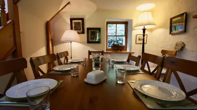 a dining room table with plates and glasses and a lamp at Glen Cottage in Comrie