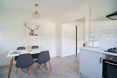 a kitchen with a table and chairs in a room at Woodside Apartment in Coatbridge