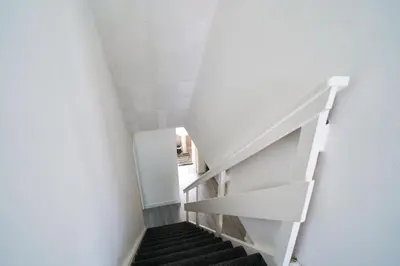 a staircase in a room with white walls and black stairs at Woodside Apartment in Coatbridge