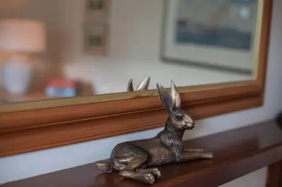 a statue of a rabbit sitting on a shelf in front of a mirror at Kennels Cottage in Killin