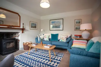 a living room with two blue couches and a fireplace at Kennels Cottage in Killin