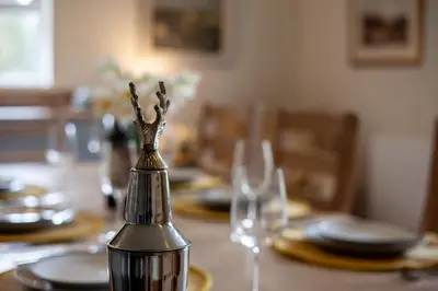 a dining room table with glasses and a tablepper on it at Kennels Cottage in Killin