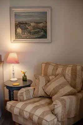 a living room with a couch and a table with a lamp at Kennels Cottage in Killin