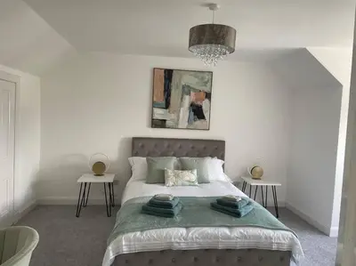 a bedroom with a large bed with two tables at Fantastic home in Brightons, Falkirk. in Polmont