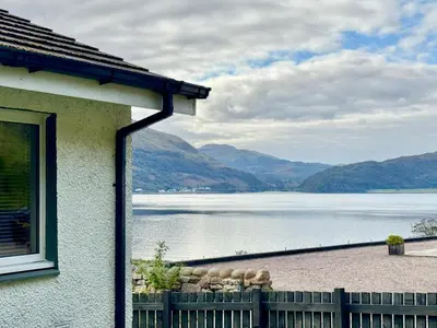 a house with a view of a lake and mountains at Ash, Birch and Rowan Self Catering Cabins in Onich