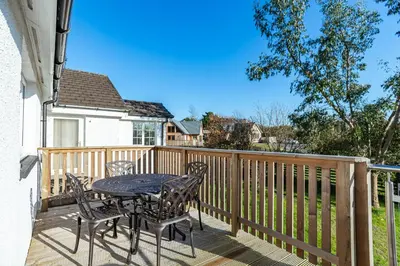 a patio with a table and chairs on a deck at Sparrowhawk Cottage with Hot Tub in Newton Stewart