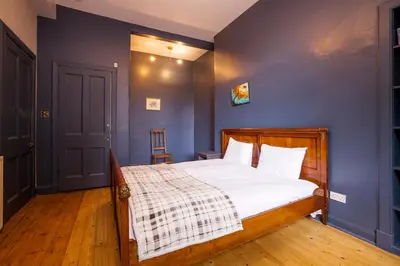a bedroom with a bed with a blue wall at JOIVY Splendid Apartment near Haymarket in Edinburgh