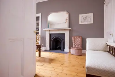 a living room with a fireplace and a mirror at JOIVY Splendid Apartment near Haymarket in Edinburgh