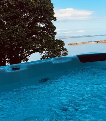 a swimming pool with blue water and a tree at Chandlers Country House in Rothesay