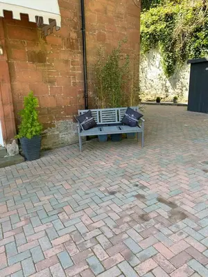 a bench with two pillows sitting on a brick patio at Chandlers Country House in Rothesay