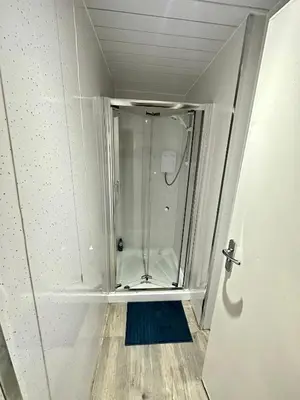 a walk in shower in a bathroom with a door at Rangers GuestHouse in Glasgow