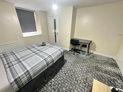 a bedroom with a bed and a desk in it at Rangers GuestHouse in Glasgow