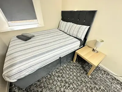 a bed with a black headboard and a small table at Rangers GuestHouse in Glasgow