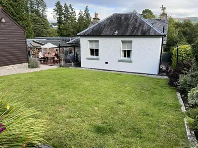 a white house with a large yard with a table at Tigh Muileann in Killin