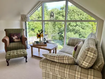 a living room with a couch and a large window at Tigh Muileann in Killin