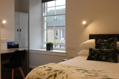 a bedroom with a bed and a desk and a window at The Arches - The Big Yin in Stirling