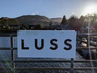 a sign on a fence that reads excuses at Heather Cottage Luss in Luss