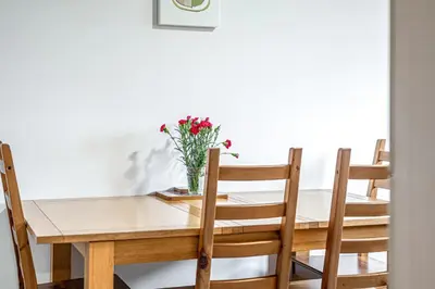 a dining room table with chairs and a vase of flowers at Super Prime Train Station Inverkeithing by TBA in Inverkeithing