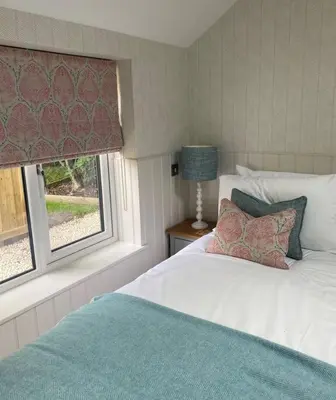 a bedroom with a white bed and a window at Hillview Cottage in Edinburgh