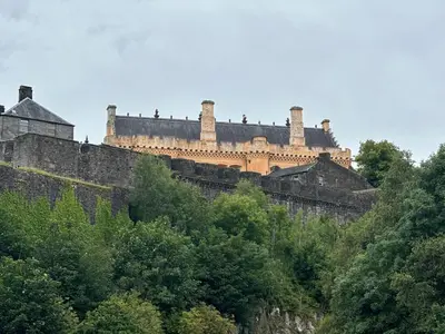 a castle on top of a hill with trees at Castle Brae Apartment in Stirling