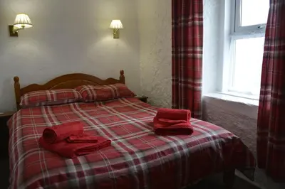 a bedroom with a bed with red towels on it at Seal Cottage in Portnahaven