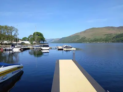 a dock with boats docked in a lake at Loch Earn Holiday Home in Saint Fillans