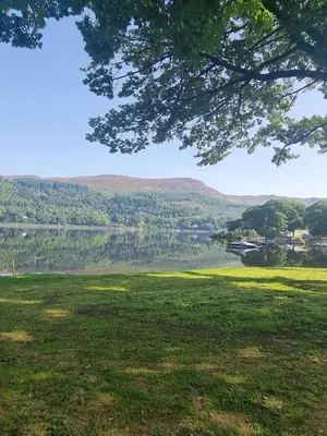 a field with a lake and mountains in the background at Loch Earn Holiday Home in Saint Fillans