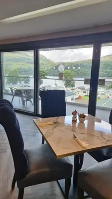 a table and chairs in a room with a large window at Loch Earn Holiday Home in Saint Fillans