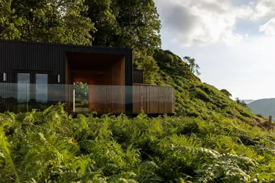 a house on top of a hill with plants at The Black Cabin Oban in Oban