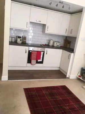 a kitchen with white cabinets and a red rug at Caledonian - Charming Central 1 Bed Flat in Edinburgh