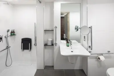 a white bathroom with a sink and a mirror at Crowne Plaza Glasgow by IHG in Glasgow