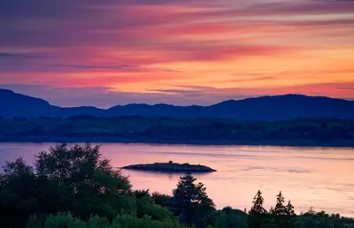an island in the middle of a lake at sunset at Isle of Eriska Hotel Spa & Island in Benderloch